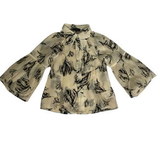 A long-sleeve blouse with a black abstract floral or brushstroke pattern on a light beige or cream base, featuring a pointed collar and a bow at the neck, laid flat against a white background.